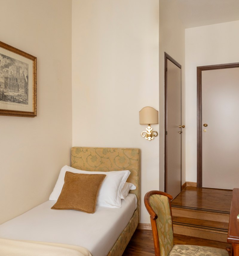 Camera singola accogliente dell'Hotel Cortina a Roma, arredata in stile classico con letto singolo e scrivania in legno. - Hotel Cortina, BZAR hotels a Roma